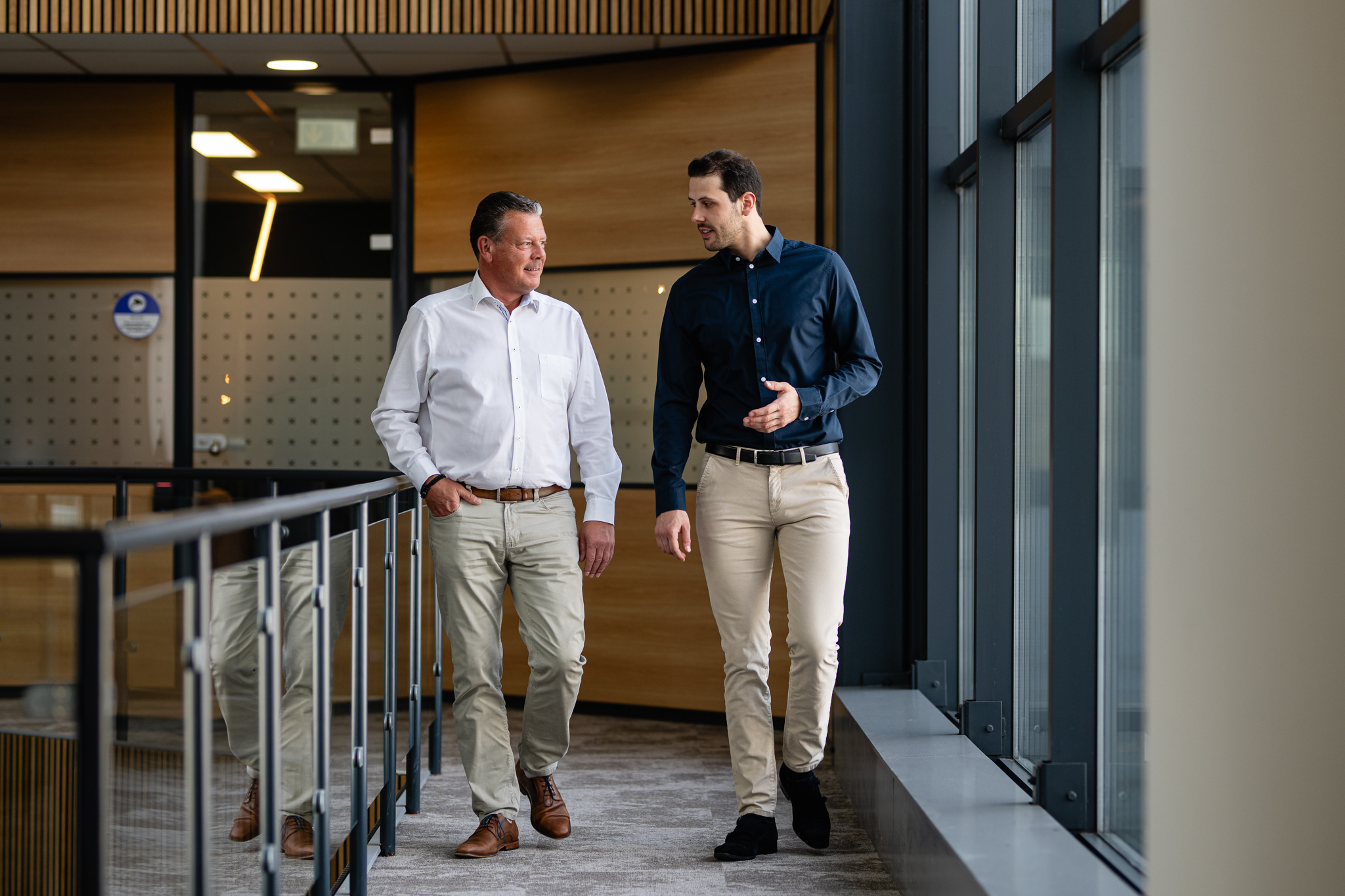 Twee mannen wandelen en praten in kantoor.